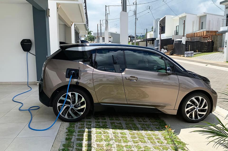 Coche eléctrico enchufado a un cargador de pared en la entrada de una casa