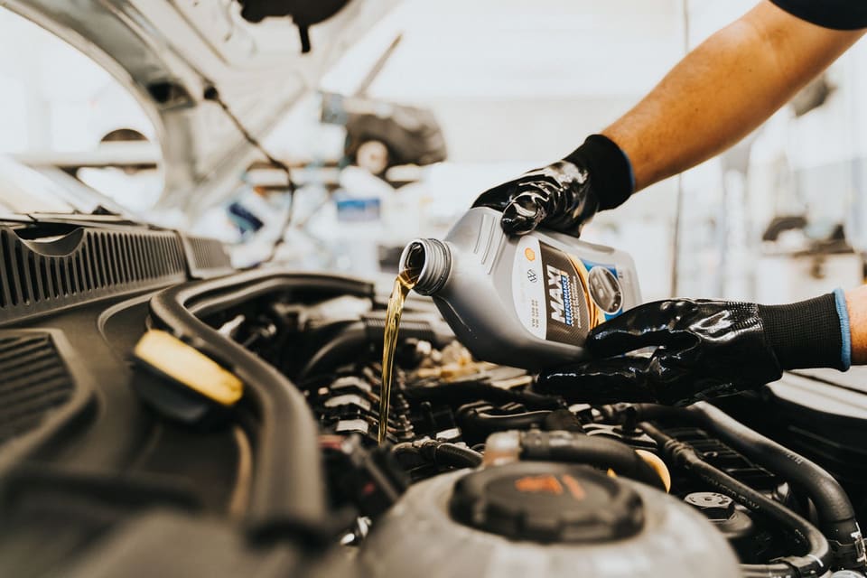 Mecánico echando aceite nuevo en el motor de un coche en un taller