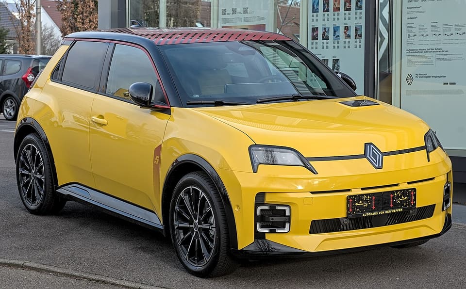 Renault 5 E-Tech eléctrico amarillo aparcado en la calle, vista frontal tres cuartos